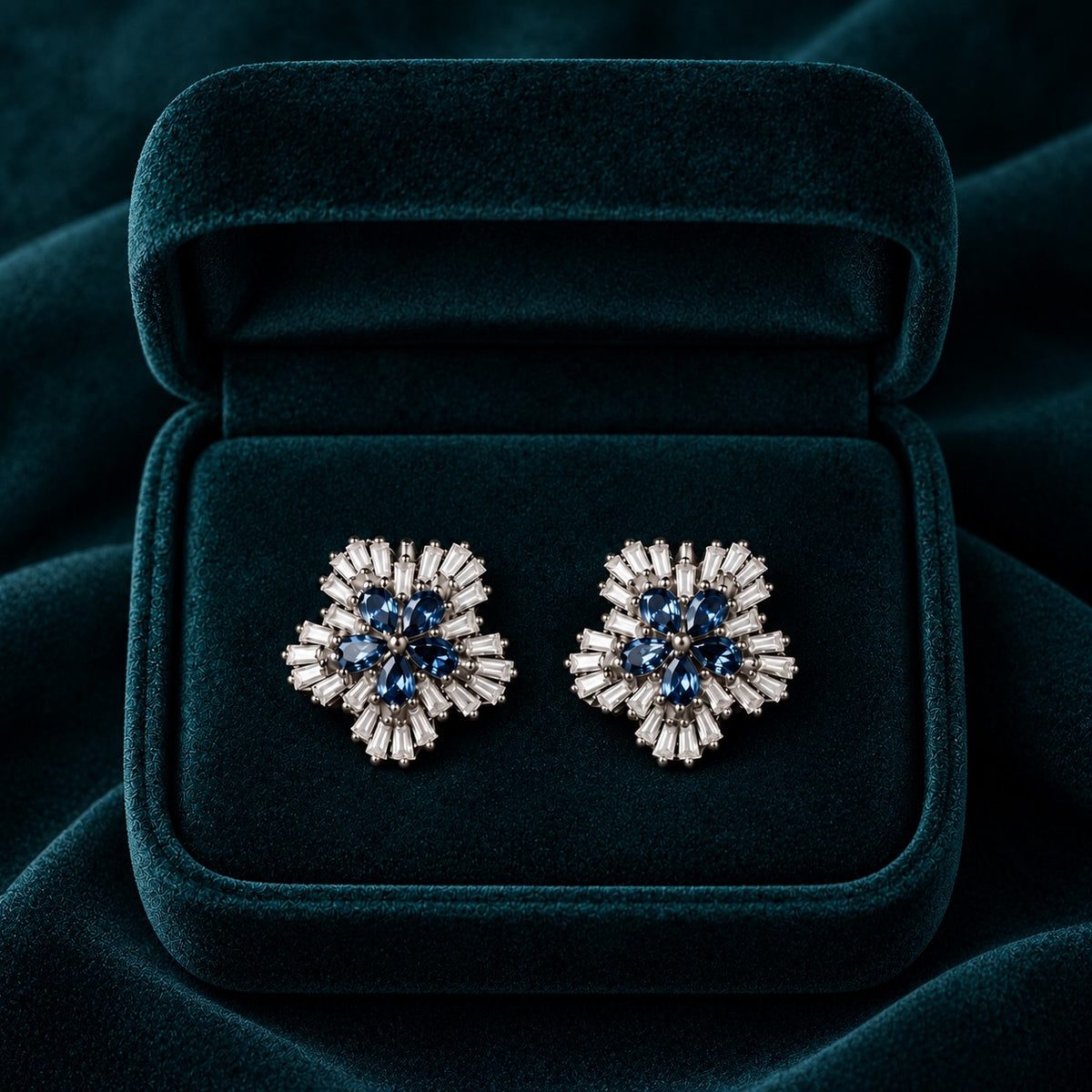 Sapphire Fan Stud Earrings featuring five pear-cut sapphire-blue stones surrounded by radiating clear baguette stones in a polished silver-tone setting