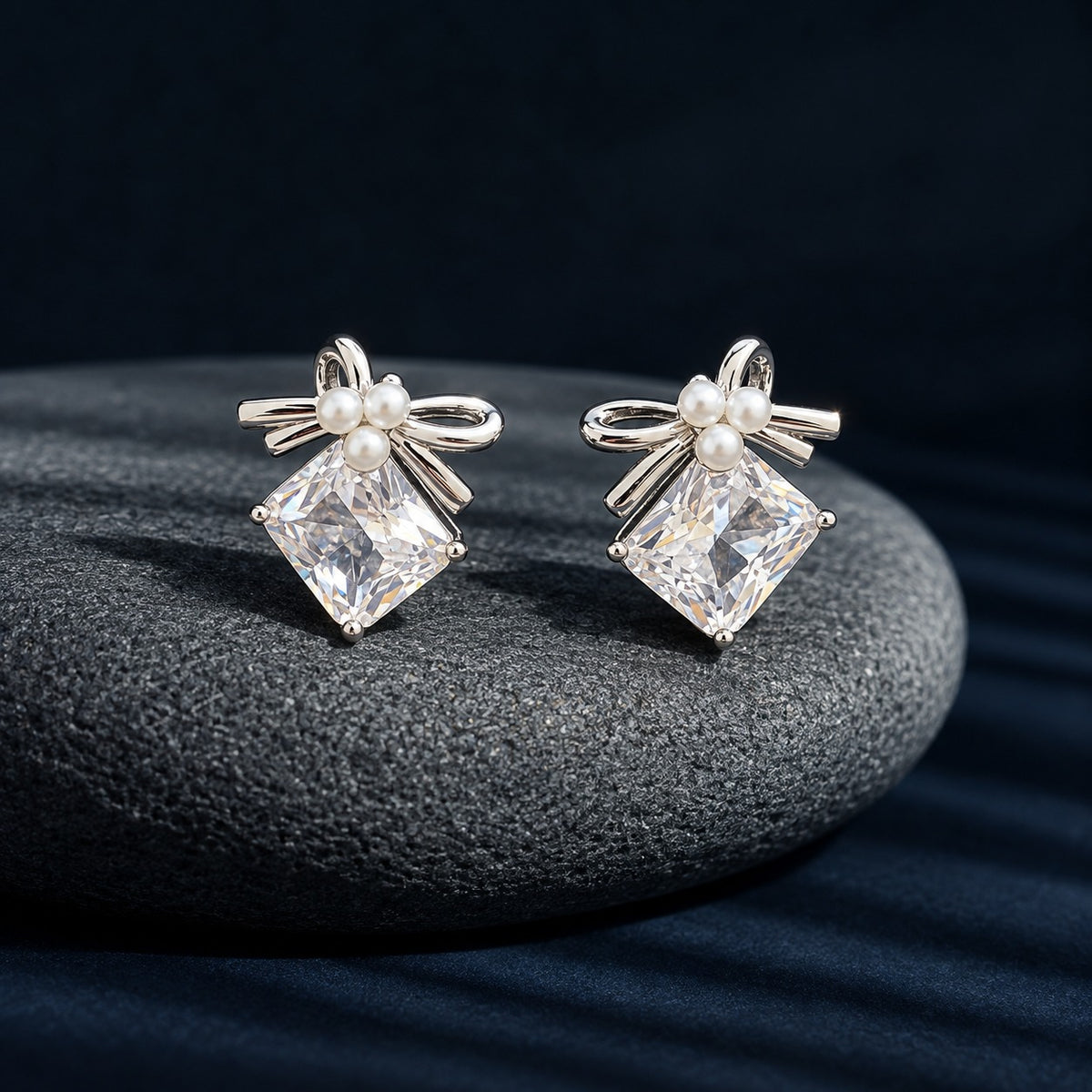 Close-up of Bowline Quartz Stud Earrings with clear diamond-shaped zircon stones, three white pearls and polished silver-tone bow detailing.