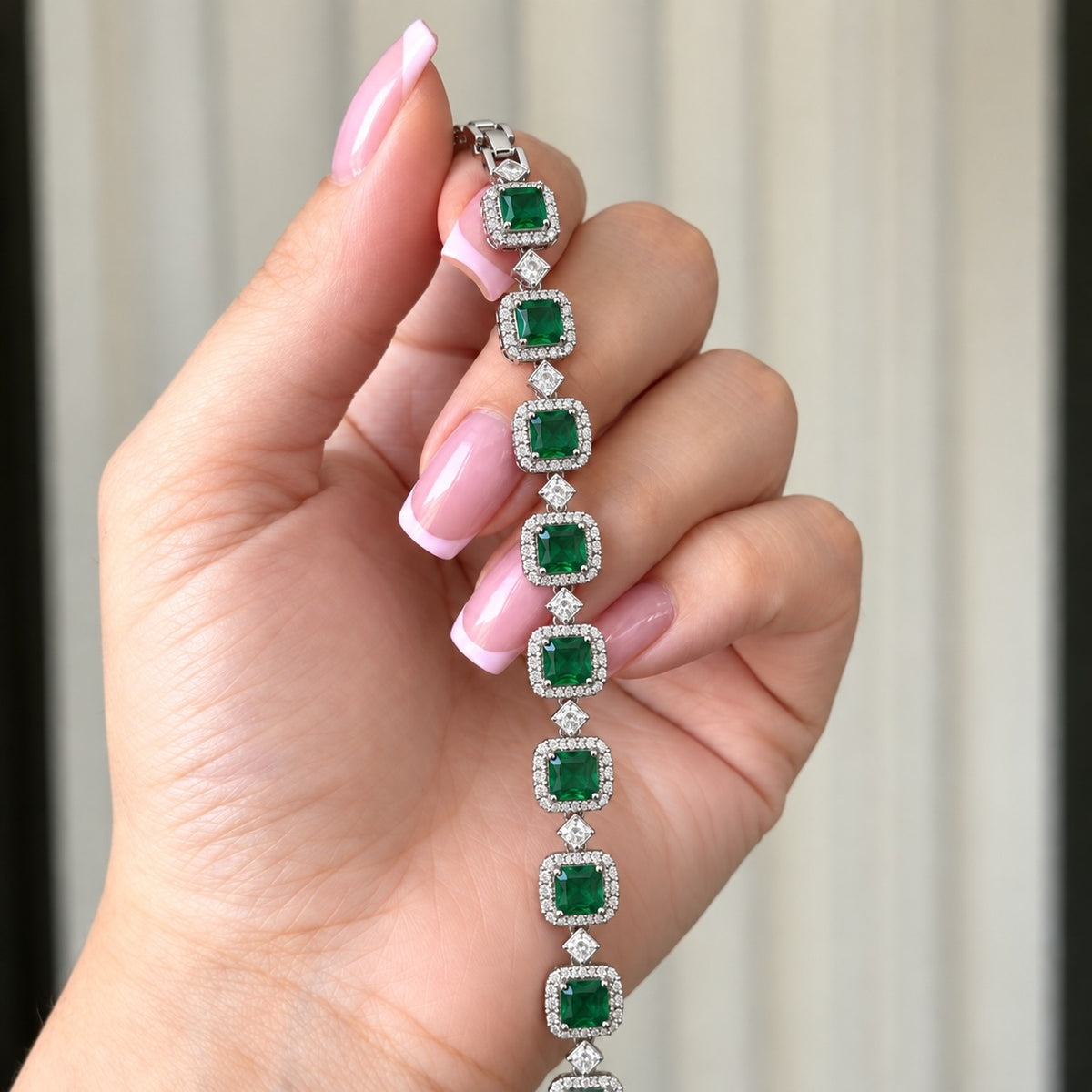 Regal Grid Bracelet held in hand, showing its square-cut gemstone settings, clear zircon borders, geometric connectors and polished silver-tone finish