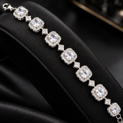 Silver-tone Regal Grid Bracelet featuring square-cut gemstones surrounded by clear zircon borders and connected with small diamond-shaped zircon links, available in ruby red, emerald green and clear zircon.