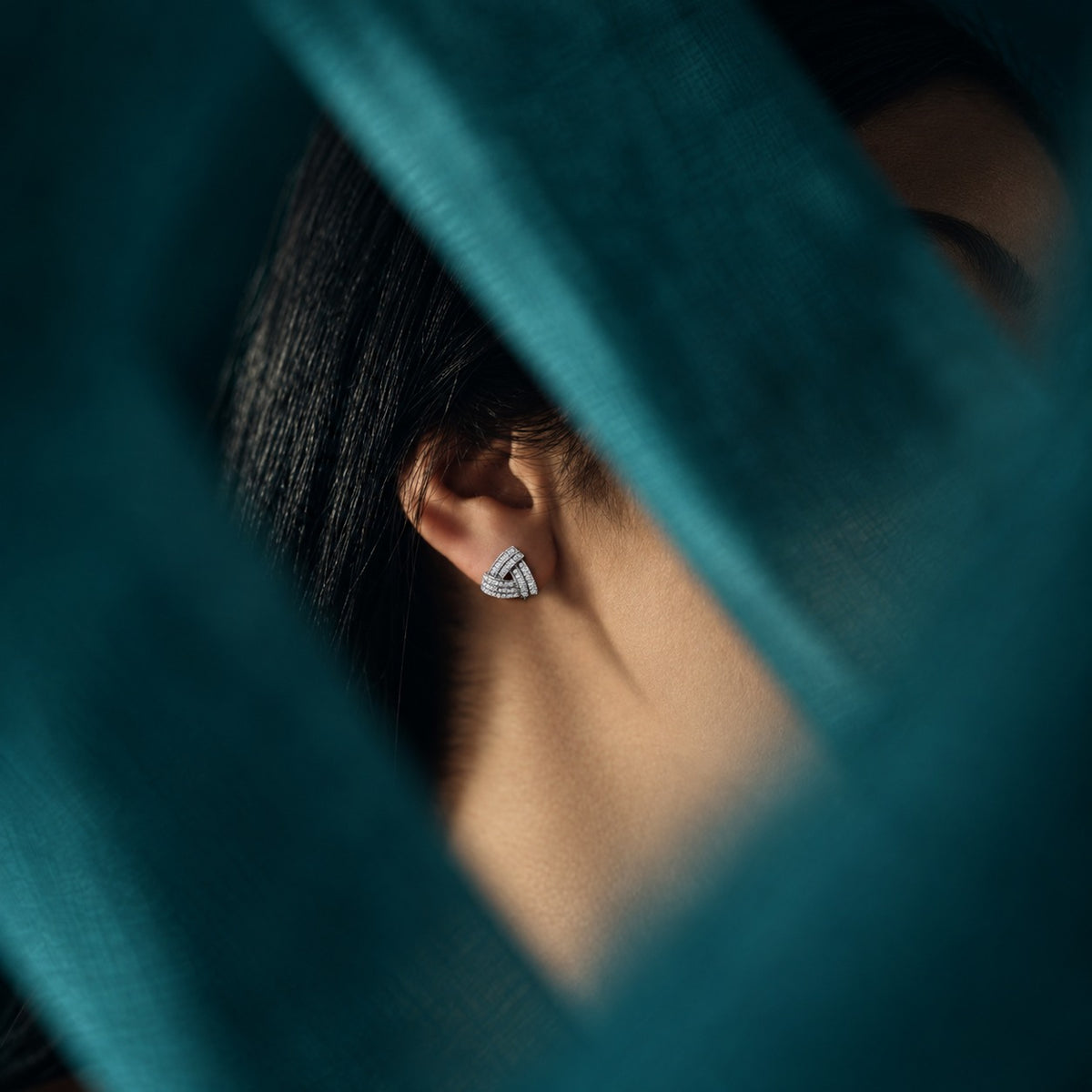 Model wearing Vela Fold S925 sterling silver zircon studs, highlighting their compact geometric shape and sculptural layered construction.