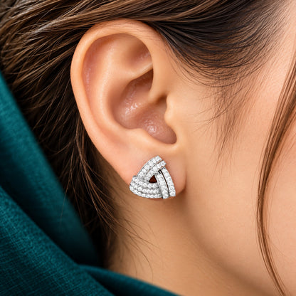 Close-up of a Vela Fold S925 sterling silver stud worn on the ear, showing its layered triangular design and clear zircon detailing