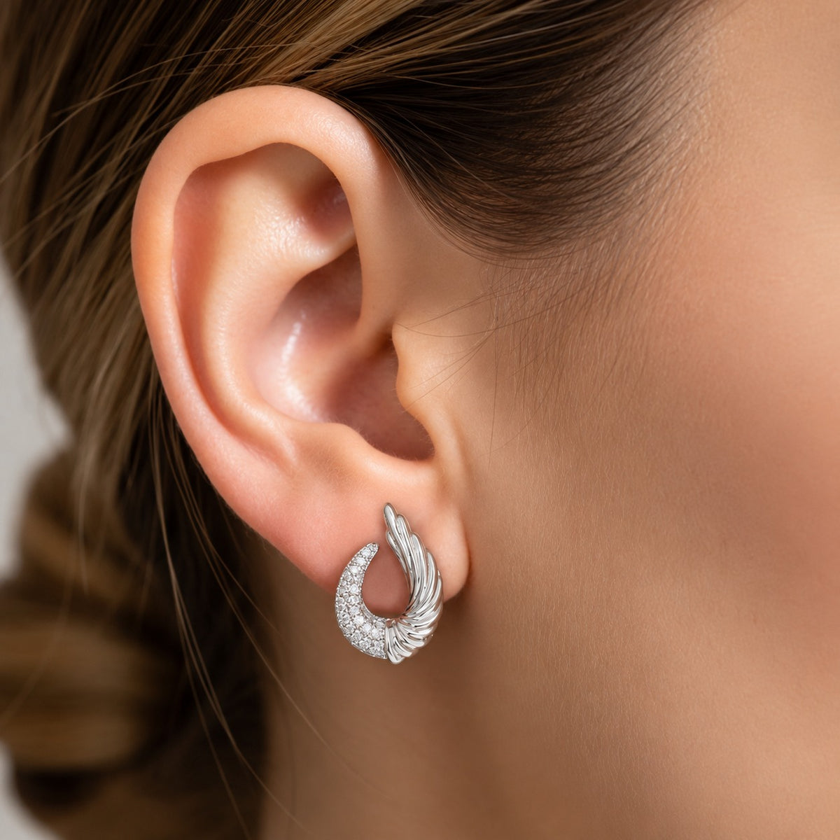 Silver Celestial Wing Crescent Stud worn on the ear, showing the curved zircon crescent and upward sculpted wing design.