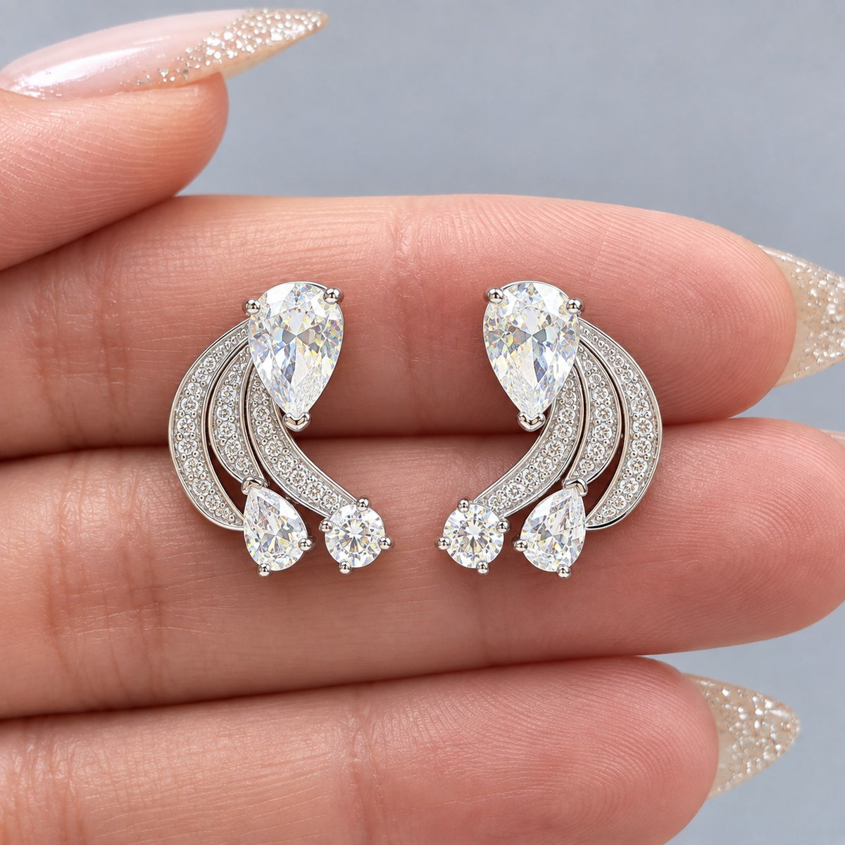 Angelique Wing Stud showing its three curved zircon wings and cascading clear stones on a hand