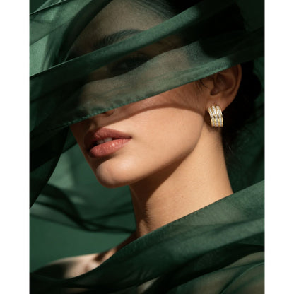 Model wearing Gilded Trio Arc Hoops featuring three gold curved bands accented with rows of clear zircons.