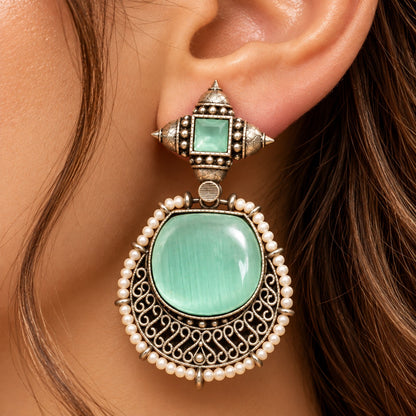 Close up of model wearing mint green Ancestral Crest earrings from The Legacy Collection.