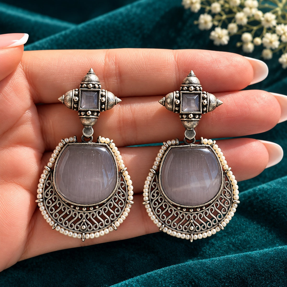 The Ancestral Crest Drops in Mist Grey with antique silver filigree and pearl detailing on  a hand