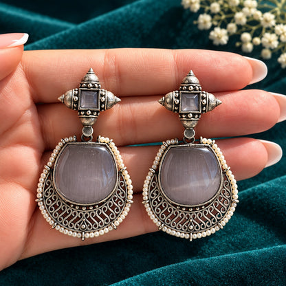 The Ancestral Crest Drops in Mist Grey with antique silver filigree and pearl detailing on  a hand