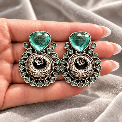 Mint green Courtyard Rose Earrings displayed on a hand, showing their statement size and intricate ornamental detailing.