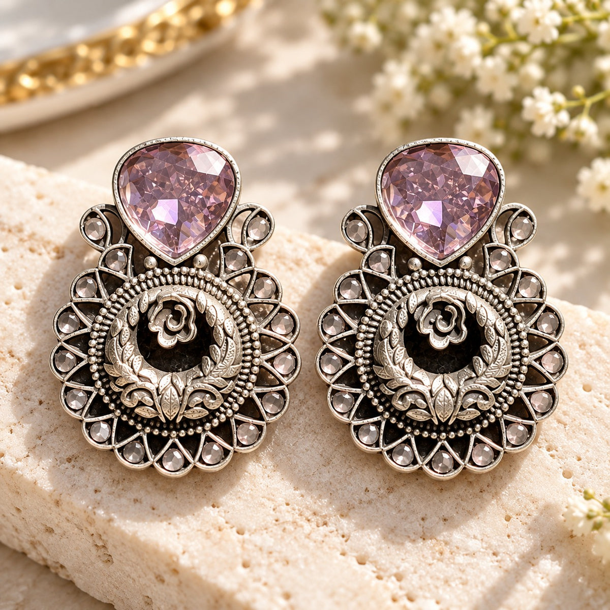 The Courtyard Rose Earrings displayed on a box, highlighting their detailed floral construction and teardrop stones.