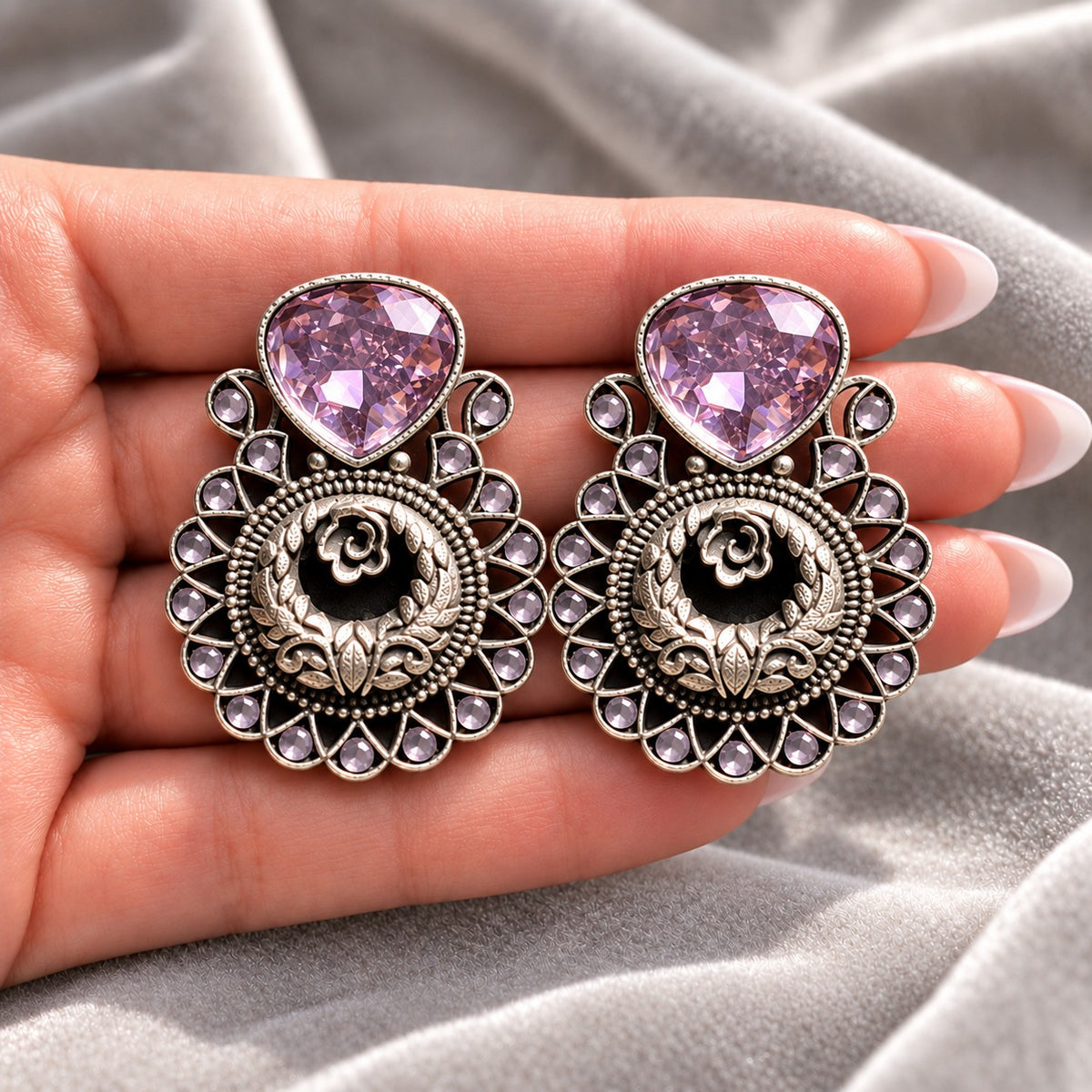 Soft Purple Courtyard Rose Earrings displayed on a hand, showing their statement size and intricate ornamental detailing.