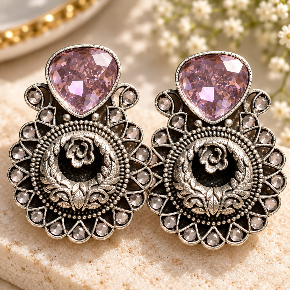 The Courtyard Rose Earrings in soft purple featuring faceted teardrop stones and ornate floral medallion detailing.