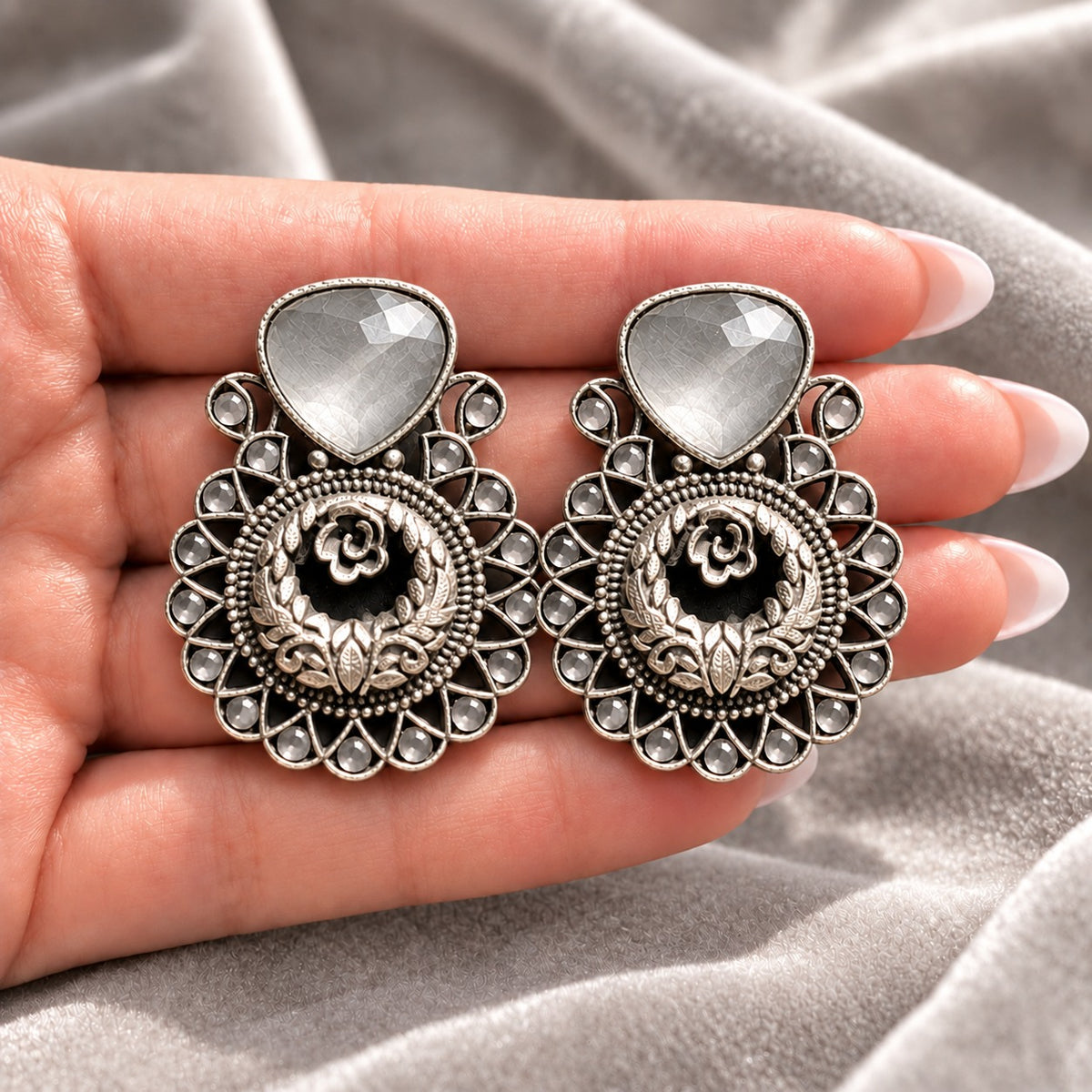 Silver Grey  Courtyard Rose Earrings displayed on a hand, showing their statement size and intricate ornamental detailing.
