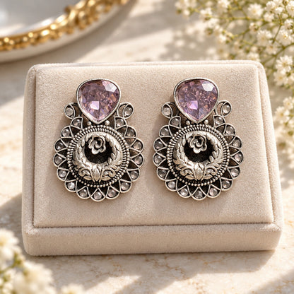 The Courtyard Rose Earrings displayed on a soft neutral jewellery box, highlighting their detailed floral construction and teardrop stones.