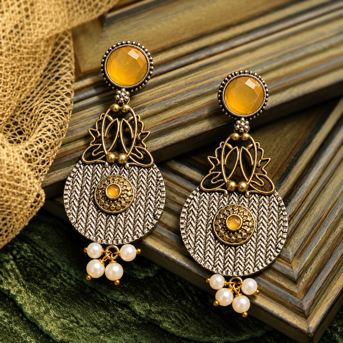 The Loom & Lotus Earrings featuring a textured silver-tone medallion, antique gold lotus detailing, faceted  mustard yellow round stones and pearl drops.