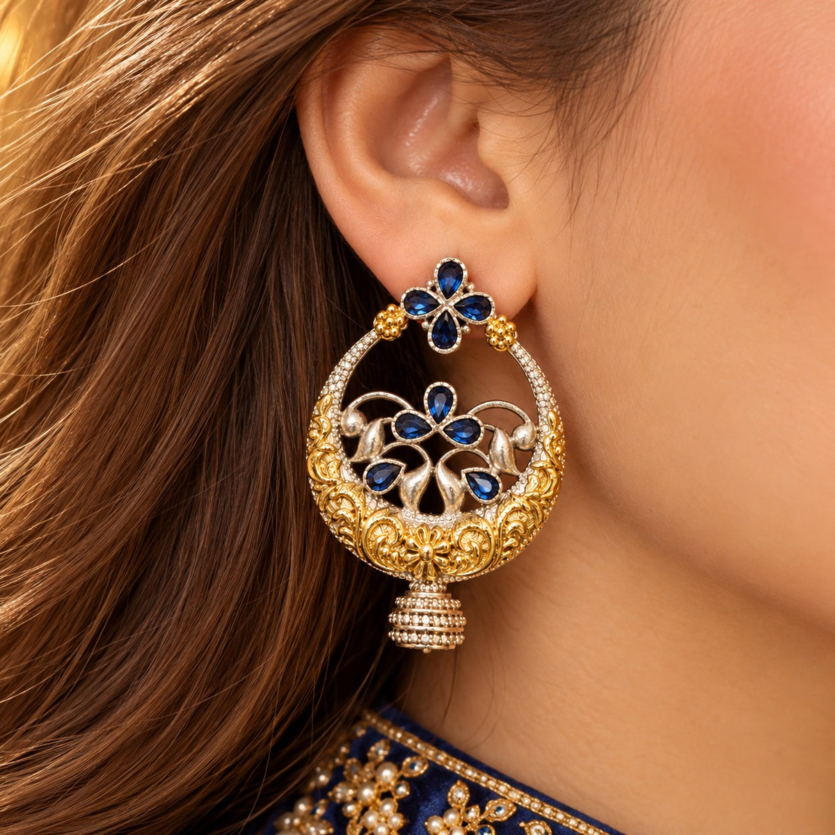 Model wearing large Azure Courtyard Earrings with sapphire-blue stones and intricate two-tone traditional detailing.