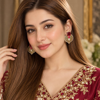 Model wearing ruby red Sovereign Court Earrings, showing the statement proportions and intricate gold-tone lattice design.