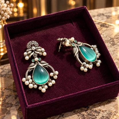 Angled view of The Royal Treasury Earrings displaying the dimensional metalwork, pearl-like embellishments and detailed teardrop setting
