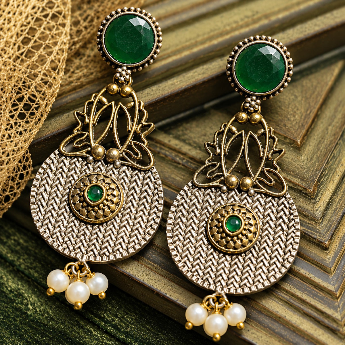 The Loom & Lotus Earrings featuring a textured silver-tone medallion, antique gold lotus detailing, faceted round  emeralg green stones and pearl drops.