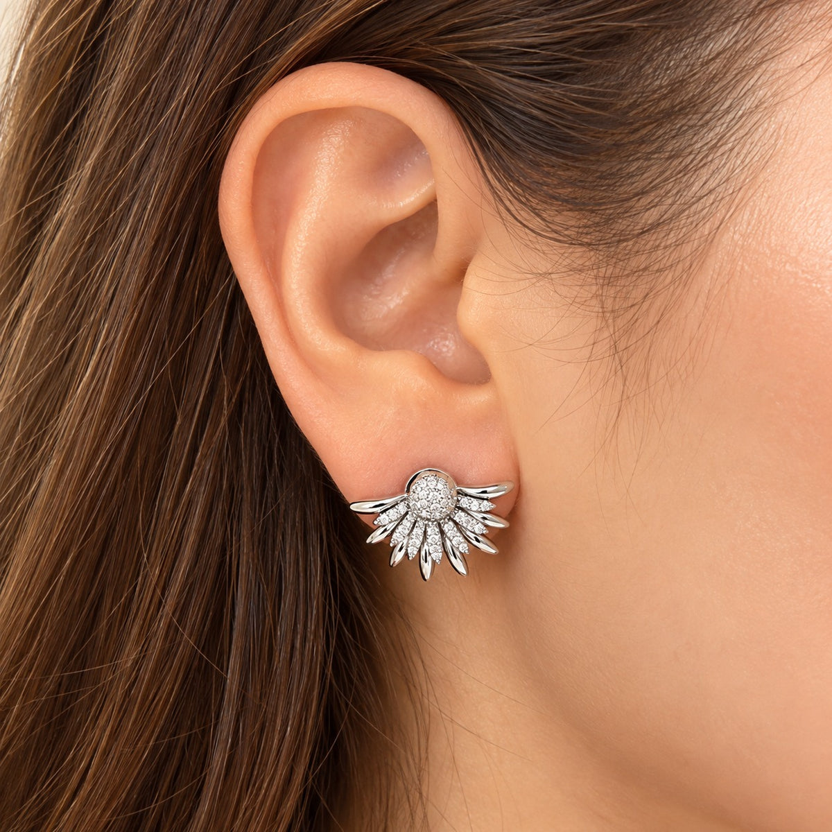 Close-up of a woman's ear wearing Silver Petal Crest Earrings, showcasing their delicate radiating petals and polished silver-tone finish.