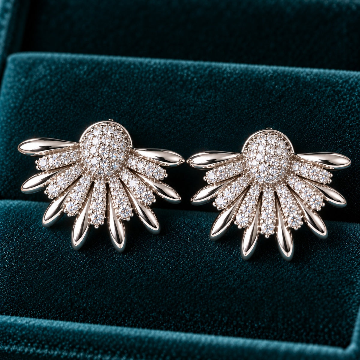 Silver Petal Crest Earrings featuring fan-shaped silver petals, clear zircon detailing and a rounded pavé-style centre against deep teal velvet.