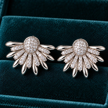 Silver Petal Crest Earrings featuring fan-shaped silver petals, clear zircon detailing and a rounded pavé-style centre against deep teal velvet.