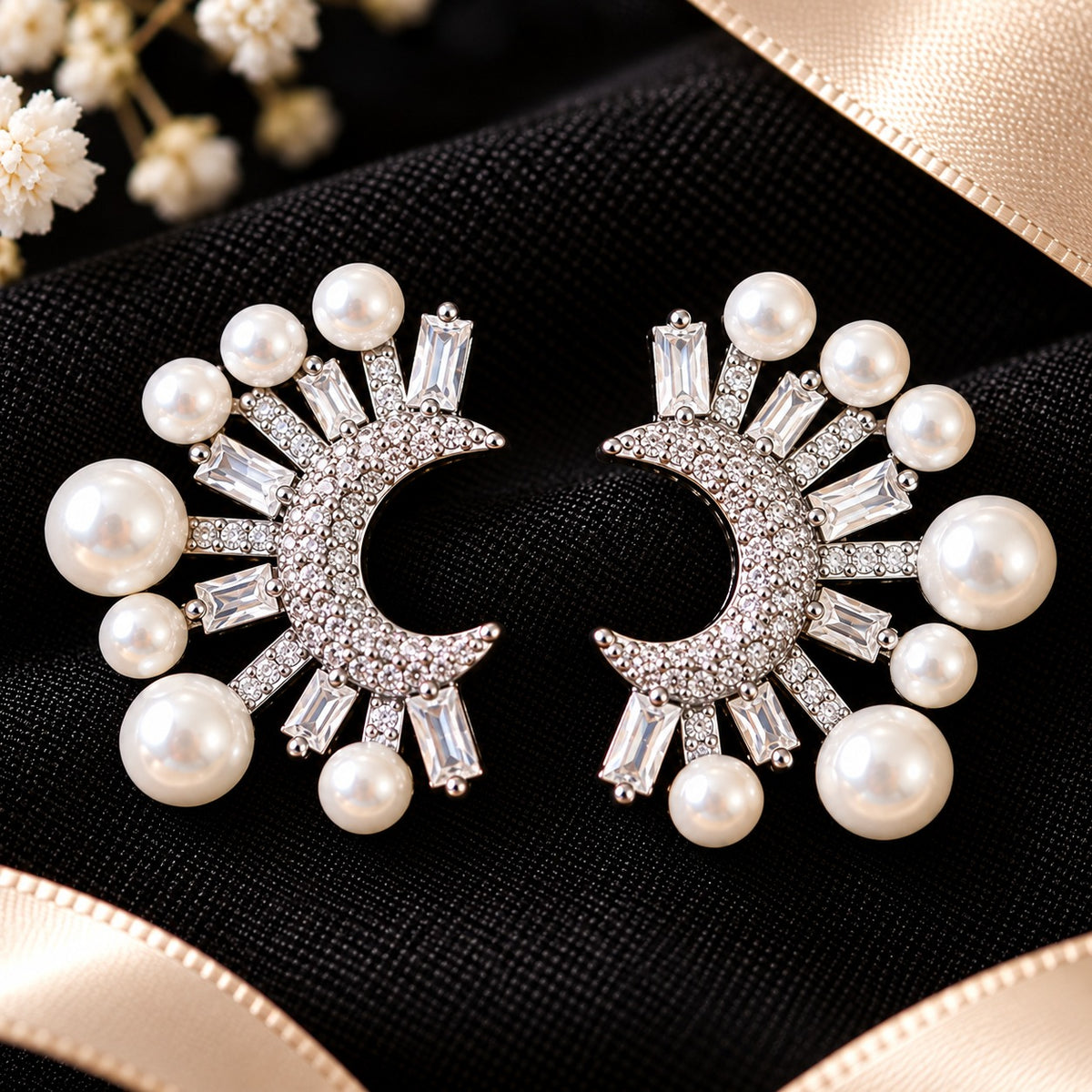Detailed close-up of crescent-shaped earrings showcasing round zircon accents, rectangular baguette-cut stones and lustrous white faux pearls arranged in a radiating pattern.