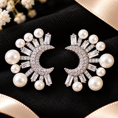 Detailed close-up of crescent-shaped earrings showcasing round zircon accents, rectangular baguette-cut stones and lustrous white faux pearls arranged in a radiating pattern.