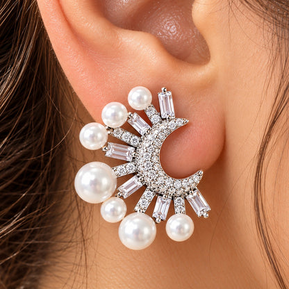 Close-up of a woman wearing silver-tone crescent pearl earrings featuring graduated white pearls and clear zircon stones in a striking statement design.
