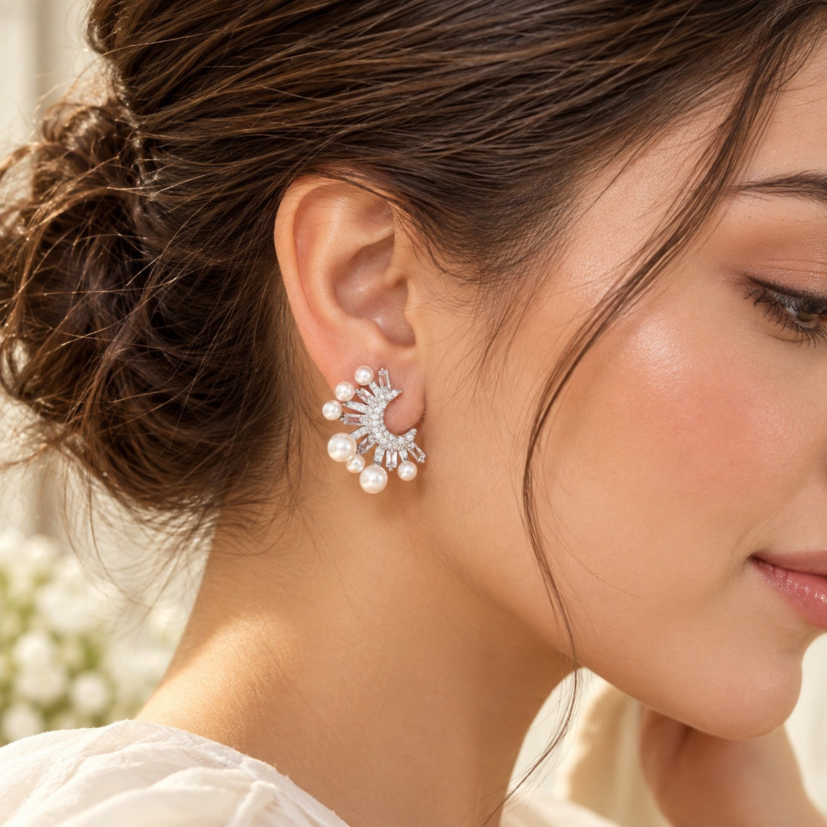 A woman wearing silver-tone crescent pearl earrings featuring graduated white pearls and clear zircon stones in a striking statement design.