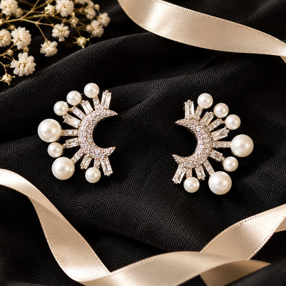 crescent-shaped earrings showcasing round zircon accents, rectangular baguette-cut stones and lustrous white faux pearls arranged in a radiating pattern.