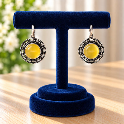 Solstice Medallion Earrings featuring a glossy lime-yellow cabochon centre, antique oxidised silver-tone finish and intricate circular beadwork.