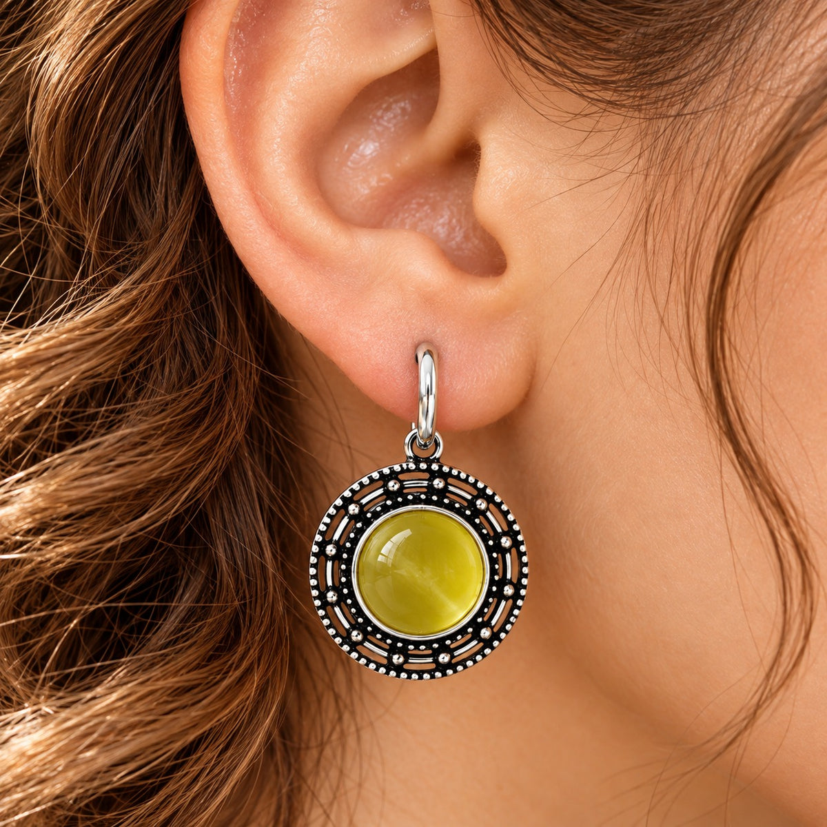 Close-up of a woman wearing olive-lime-green Solstice Medallion Earrings with an antique oxidised silver-tone circular frame
