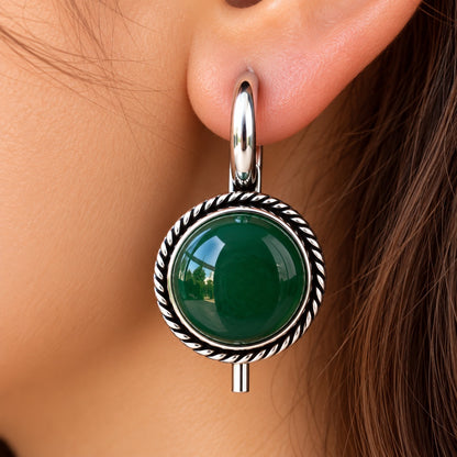 Model wearing Regent Cabochon Earrings, showcasing the round domed centre, vintage-inspired twisted border and polished silver-tone hoop.