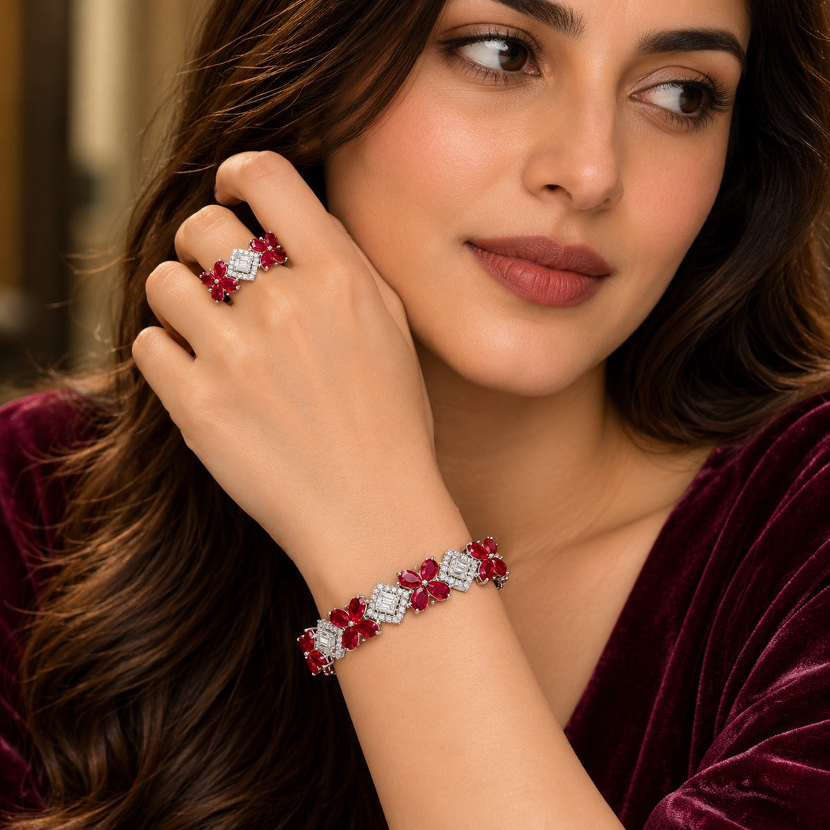 Woman wearing a ruby red floral bracelet and matching ring, featuring brilliant zircon centrepieces and delicate flower-shaped gemstones.