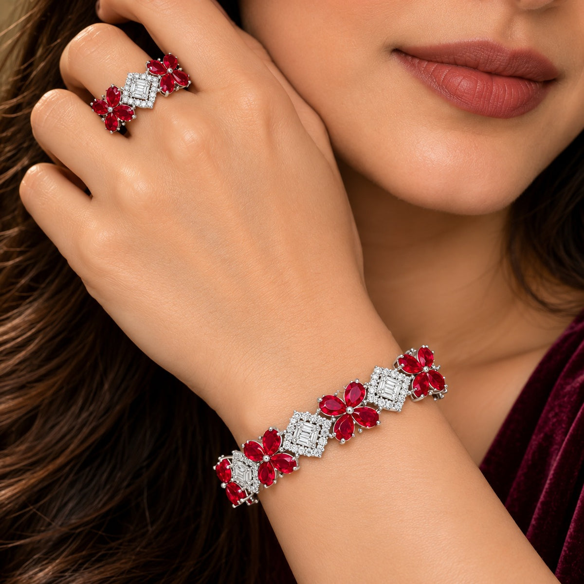 Woman wearing a ruby red floral bracelet and matching ring, featuring brilliant zircon centrepieces and delicate flower-shaped gemstones.