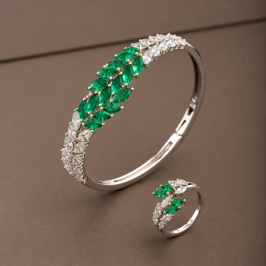 Emerald green and clear zircon bracelet and ring set featuring a silver-tone leaf-inspired design on a taupe background.