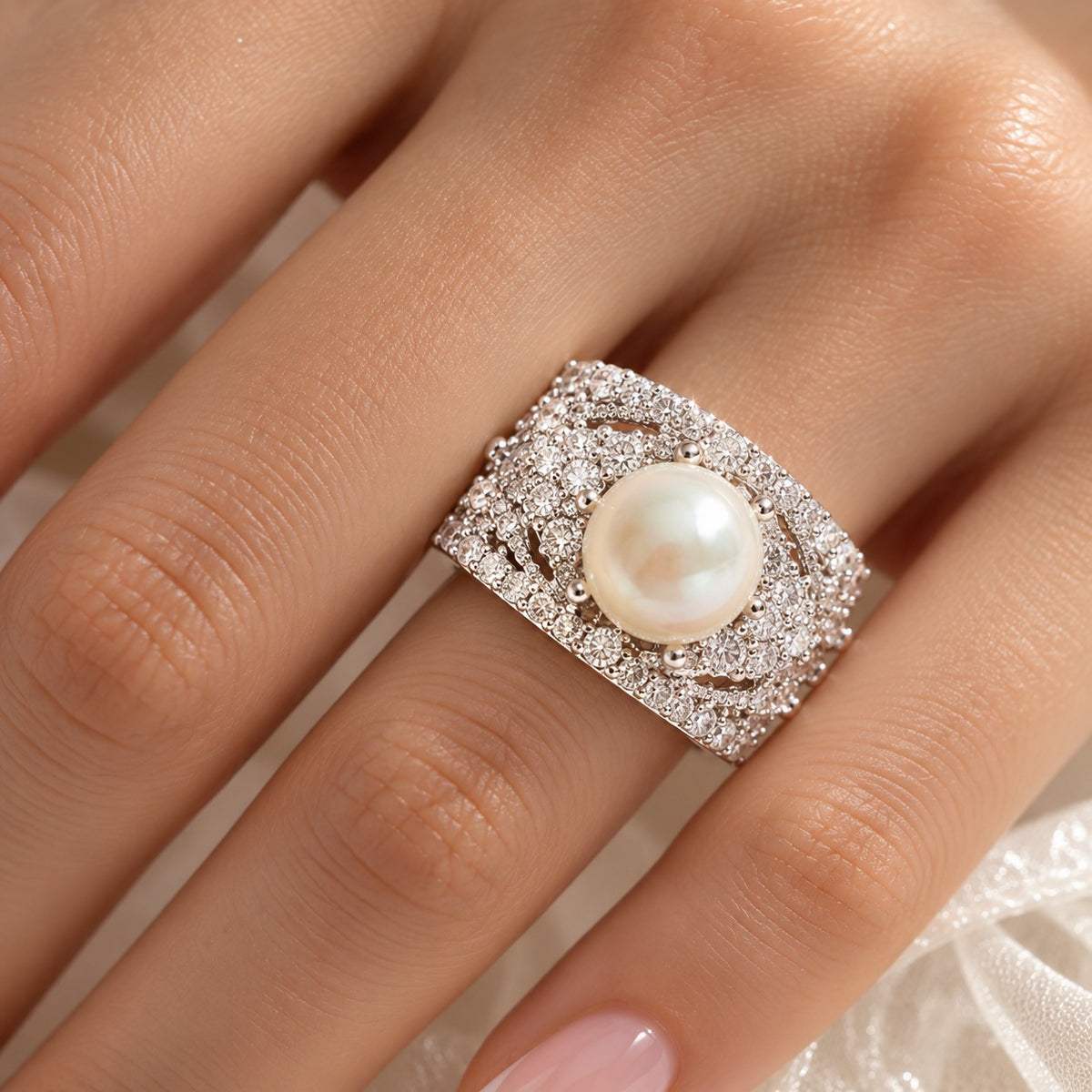 Close-up of a woman's finger wearing the Pearl Empress Zircon Ring, highlighting its luminous pearl centre, layered zircon embellishments and elaborate silver-tone design.