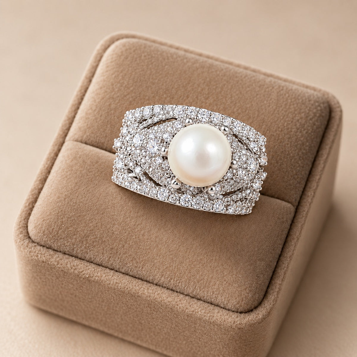 Pearl Empress Zircon Ring featuring a large ivory-white pearl surrounded by intricate clear zircon detailing in a wide silver-tone band, displayed on a beige velvet ring stand
