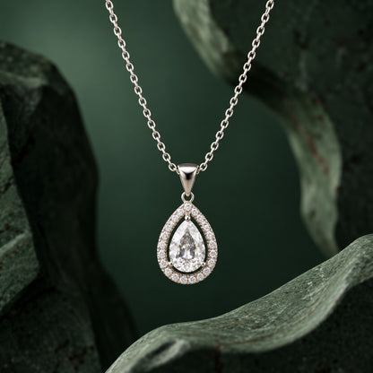 Aurelle Pear Zircon Pendant displayed against a dark green sculptural backdrop, showcasing its teardrop design and clear zircon stones.