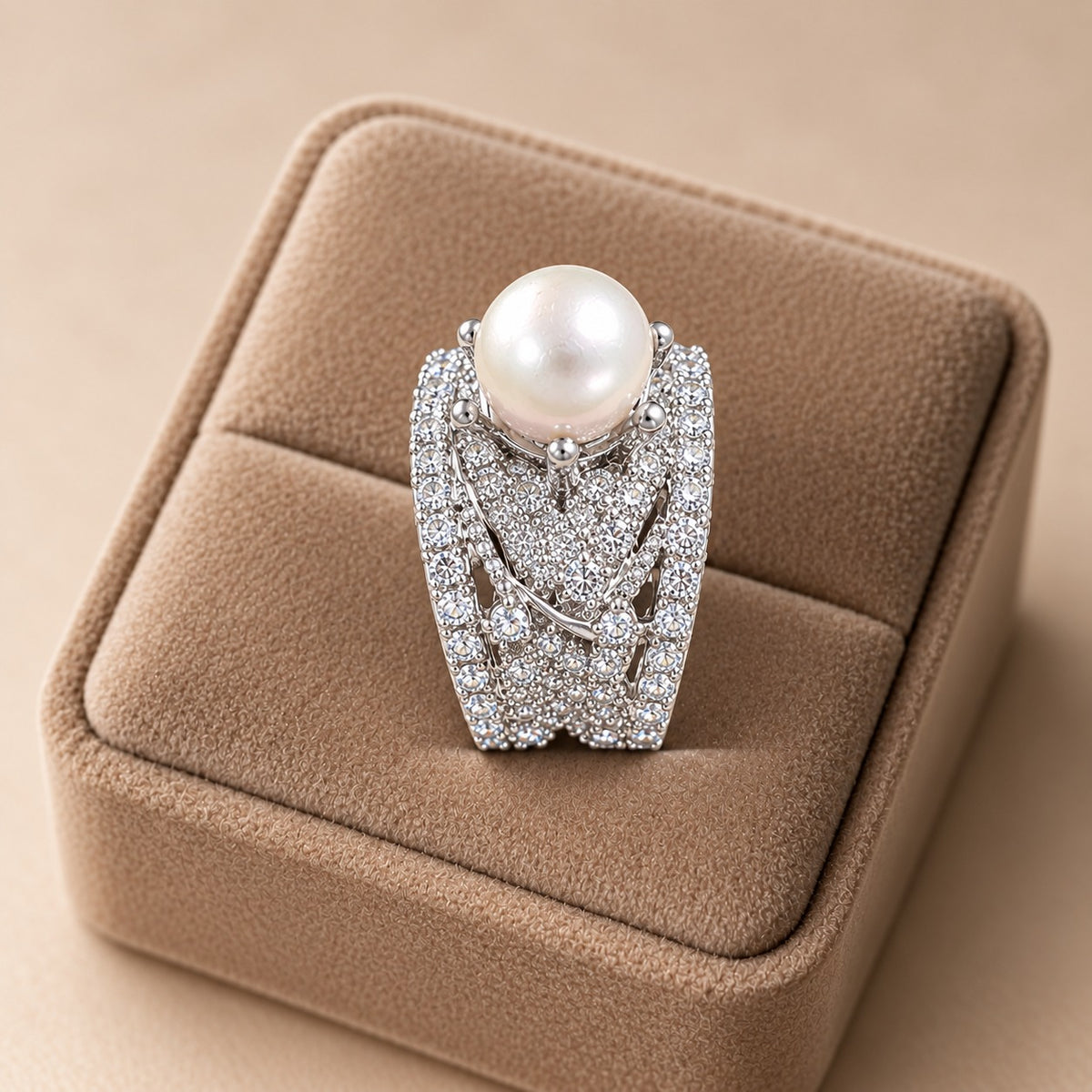 Side-angle view of the Pearl Empress Zircon Ring on a beige velvet display, showcasing its raised pearl setting, wide structured band and intricate openwork zircon detailing.