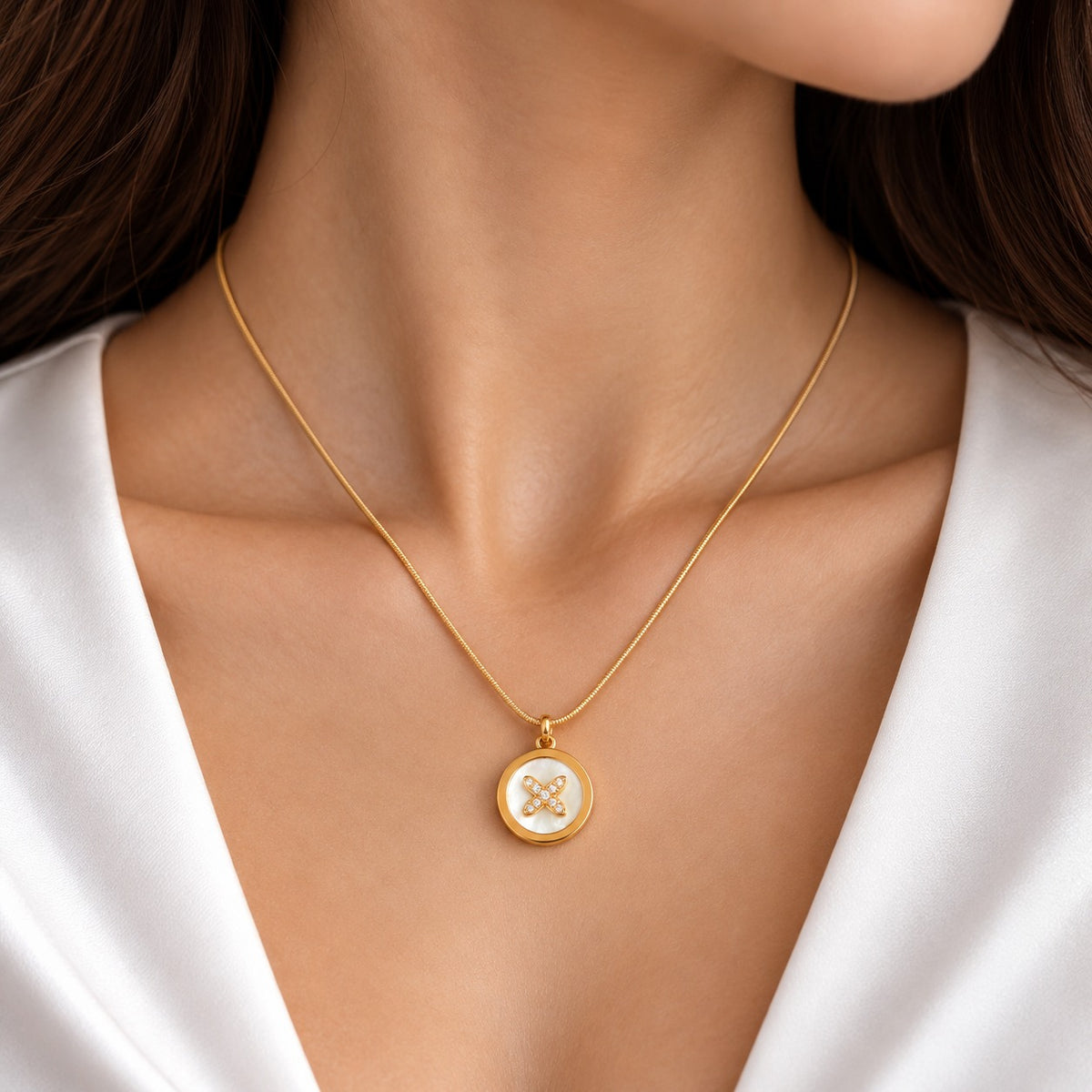 Close-up of a woman wearing the Aurelia Pearl Medallion Pendant on a delicate gold-tone chain, featuring a round pearl-white centre and a zircon-studded four-petal floral design, styled with a white outfit