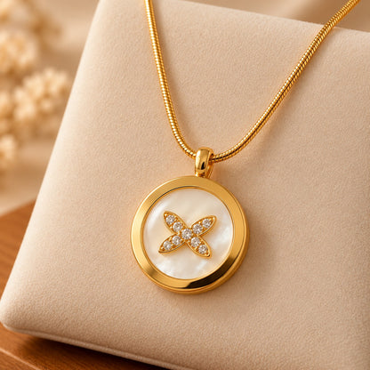 Detailed view of a gold-tone circular medallion pendant featuring a smooth polished border, iridescent pearl-white centre and clear zircon floral embellishment.
