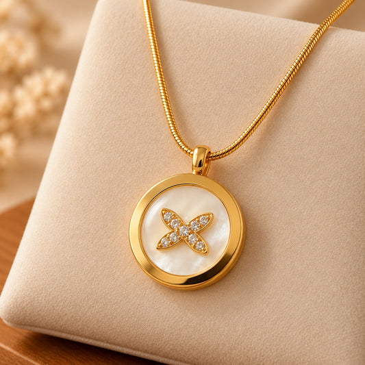 Detailed view of a gold-tone circular medallion pendant featuring a smooth polished border, iridescent pearl-white centre and clear zircon floral embellishment.