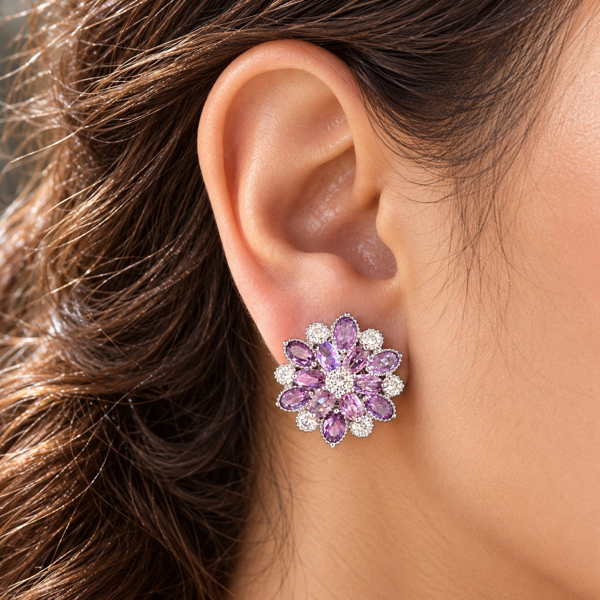 Close-up of a woman's ear wearing the Vespera Bloom amethyst purple floral stud earring, featuring vivid red gemstone petals and brilliant clear zircon detailing.