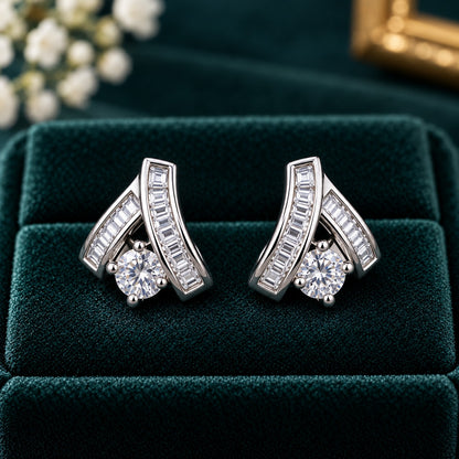 Veyra Duet silver-tone zircon stud earrings featuring two angled baguette-cut zircon bands and a brilliant round-cut clear zircon, displayed on luxurious deep teal velvet.