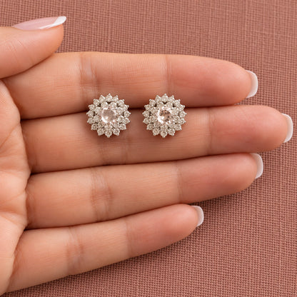 A pair of  Kensington Cluster Studs resting on a woman's fingers, showing their compact proportions, mint-green centre stones and intricate zircon surrounds.