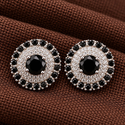 Detailed close-up of the Regent Medallion Studs in black, revealing the faceted centre stone, finely arranged clear zircons, and surrounding ruby red gemstones.