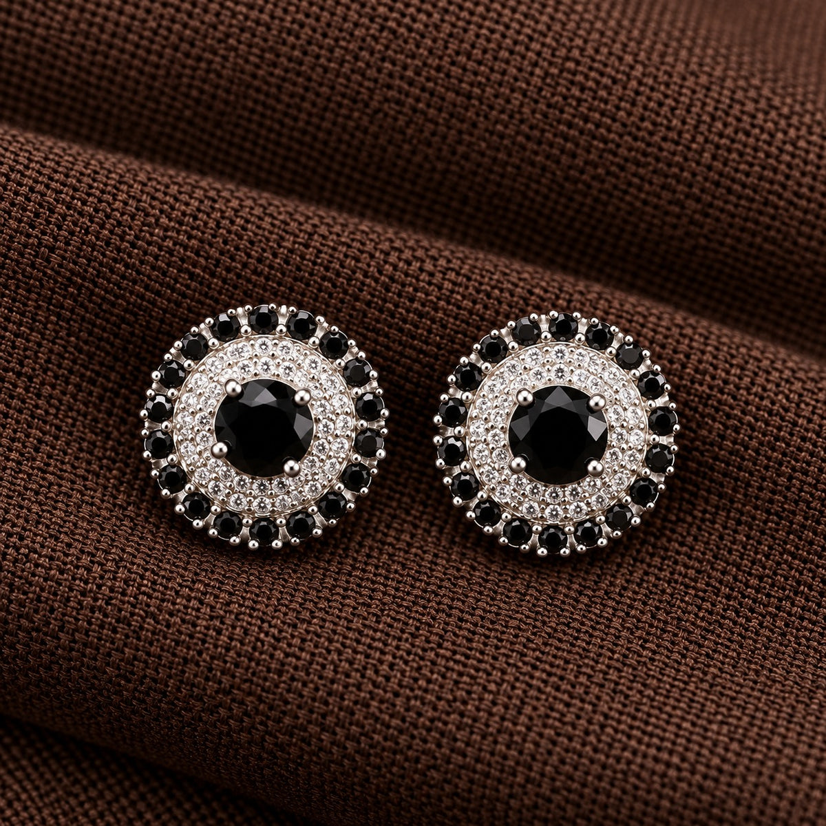 Regent Medallion Studs featuring a faceted  black centre stone, delicate clear zircon detailing, and an outer circle of black gemstones in a polished silver-tone setting.