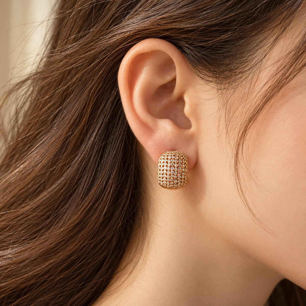 Side-profile view of a model wearing Gilded Mosaic Huggie Earrings, showcasing their compact huggie shape, dimensional stone setting and polished gold-tone finish